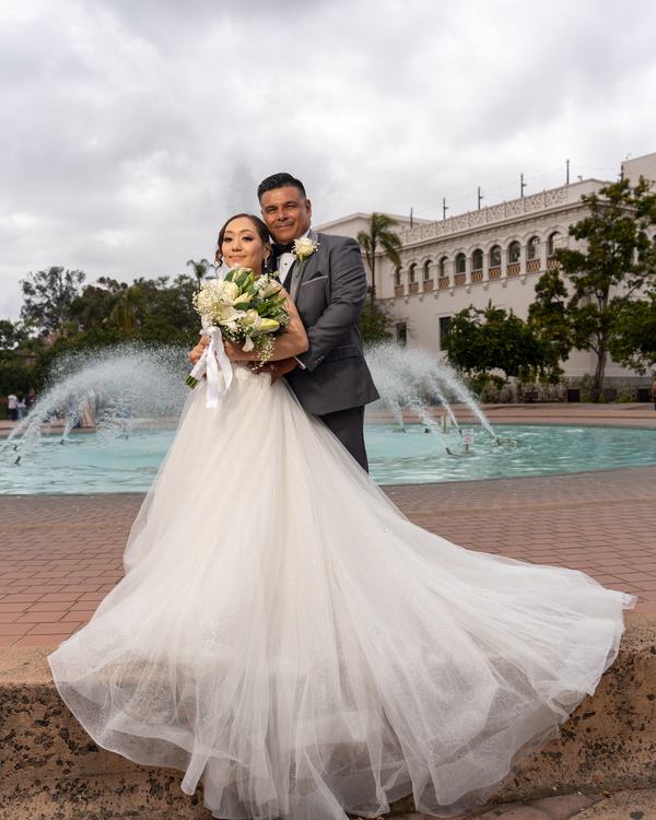 Pareja de novios abrazados frente a una fuente